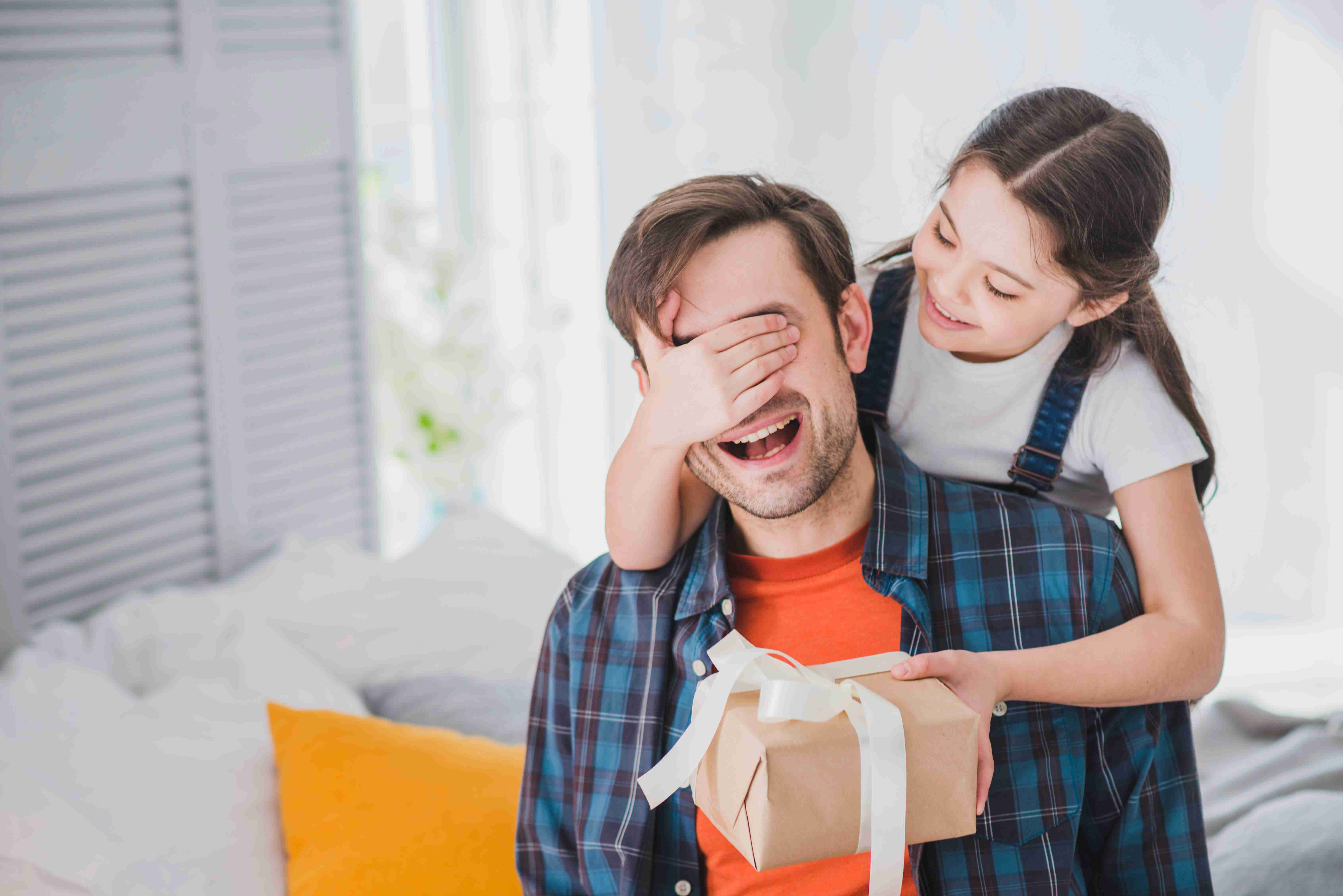 Father’s Day-themed image showing a daughter covering her father’s eyes while presenting a gift
